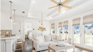 A spacious living room with a white sofa, a wooden coffee table, and a ceiling fan. - Prominence Salt & Light - 6 Seat Golf Cart Included (Walton County)