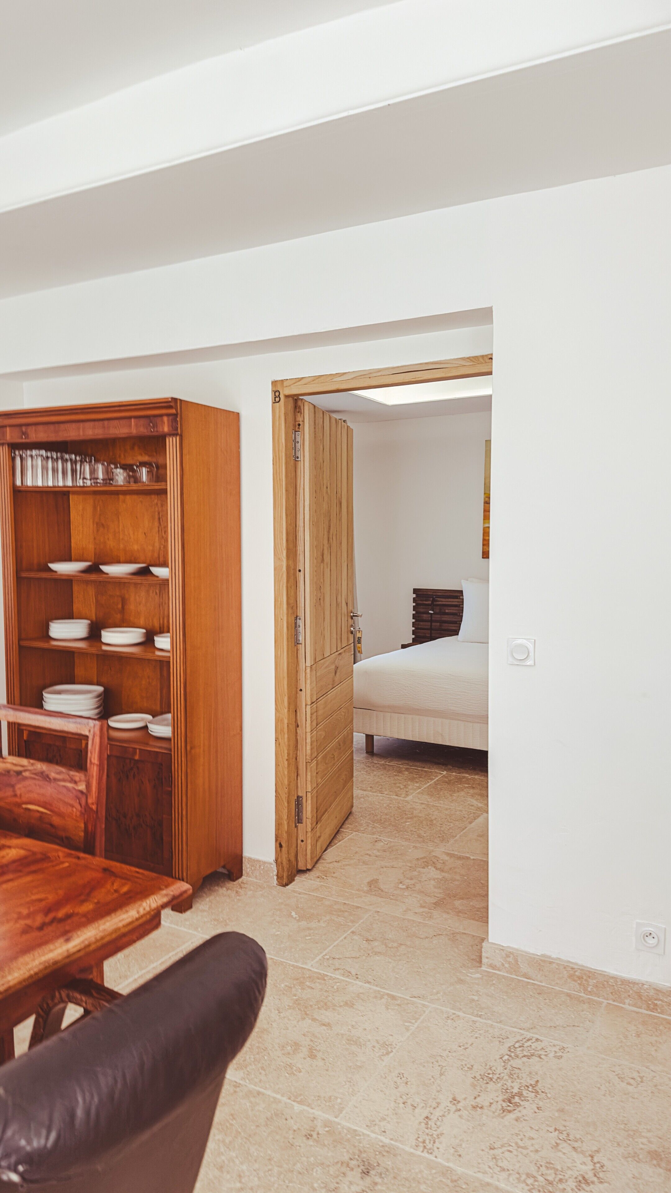 Een kamer met een houten kast, een bed en een betegelde vloer.