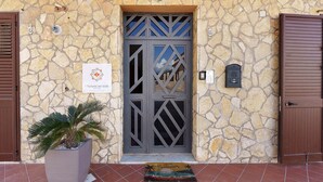 A stone facade with a decorative door, a potted plant, and a welcome mat. - Room '1' with Sea View, Wi-Fi and Air Conditioning (Balestrate)
