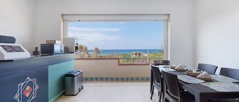 A balcony with a dining table and chairs, a microwave, and a trash bin.