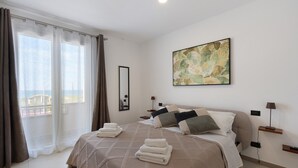 A hotel room with a bed, a large window with curtains, a painting on the wall, and a nightstand with a lamp. - Room '1' with Sea View, Wi-Fi and Air Conditioning (Balestrate)