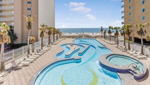 A pool area with multiple swimming pools, palm trees, and a view of the beach. - Crystal Tower 906 (Gulf Shores)