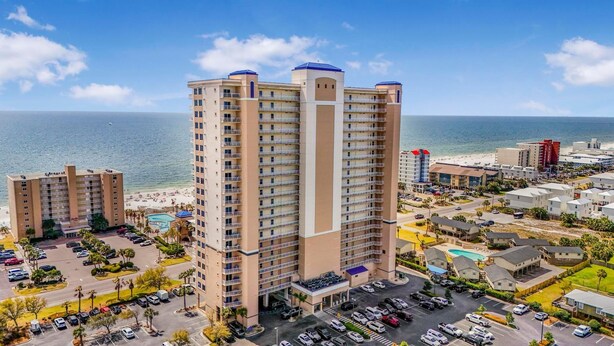 A high-rise hotel with multiple balconies, a swimming pool, and a beach view. - Crystal Tower 906 (Gulf Shores)