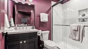 Een moderne badkamer met een wastafel, toilet, douchegedeelte en een glazen douchecabine.