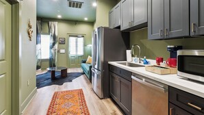 A compact kitchen with dark cabinets, a stainless steel refrigerator, and a microwave. - Vibrant NOLA Retreat Jazz & Culture (New Orleans)