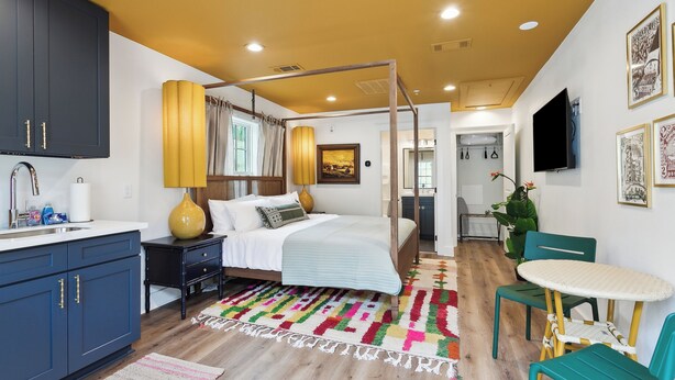 A bedroom with a bed, bedside table, lamp, and a view of the bathroom. - Vibrant NOLA Retreat Jazz & Culture (New Orleans)
