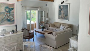 A spacious living area with a sofa, a dining table, and a view of the outdoors through a sliding door. - LVAM – Villa Maraval · 8 Guests · 4 Bedrooms · Swimming Pool (Agde)