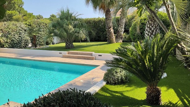 A swimming pool surrounded by well-maintained grass and various trees, including palm trees. - LVAM – Villa Maraval · 8 Guests · 4 Bedrooms · Swimming Pool (Agde)