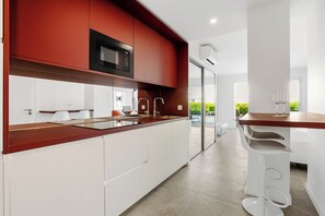 A modern kitchen with a red and white color scheme, a built-in microwave, and a glass door leading to a balcony.