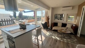 A modern living space with a kitchen, dining area, and a sofa set. - Naturiste Cap d'Agde Villa Port Nature 187 (Agde)