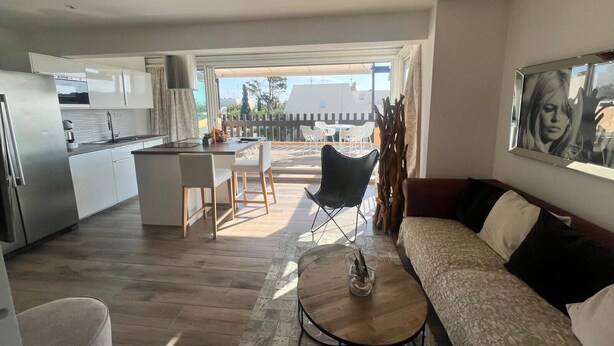 A modern living room with a sofa, a coffee table, and a dining area with chairs and a table. - Naturiste Cap d'Agde Villa Port Nature 187 (Agde)