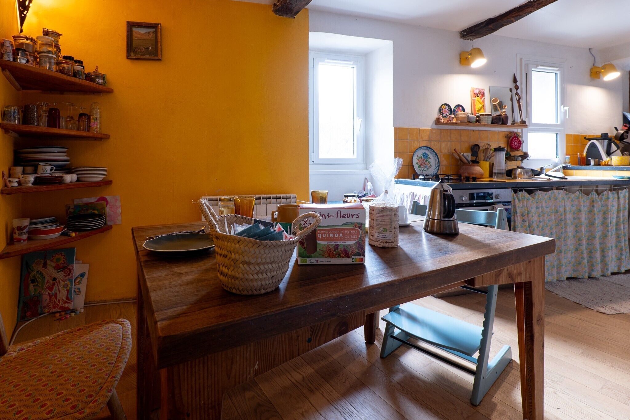 Une cuisine avec des étagères en bois, une table à manger et une fenêtre.