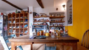 Een keuken met houten planken, een eettafel, stoelen en diverse keukenspullen.