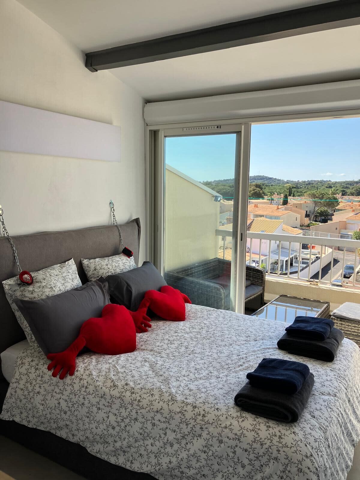 Et soveværelse med en stor seng, udsigt over byen og en balkon.