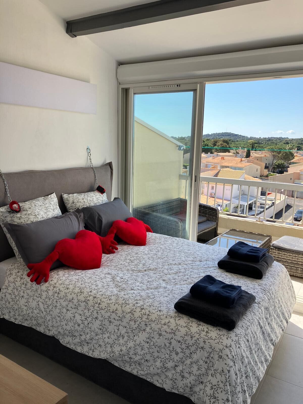 Quarto com cama grande, varanda com vista para edifícios e porta de vidro deslizante.