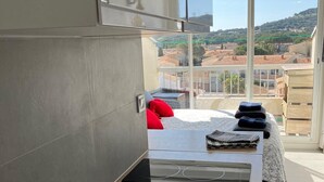Une salle de bain moderne dotée d’un grand lavabo, d’un espace douche et offrant une vue sur le paysage urbain grâce à de grandes fenêtres.