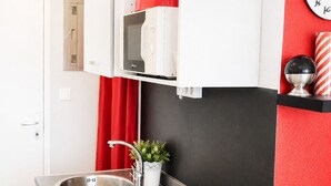 Een compacte keuken met een ingebouwde magnetron, een spoelbak en een zwarte vaatwasser.
