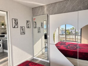 A modern bedroom with a bed, a large mirror, and artwork on the wall. - Naturiste Cap d'Agde Héliopolis F 90 (Agde)