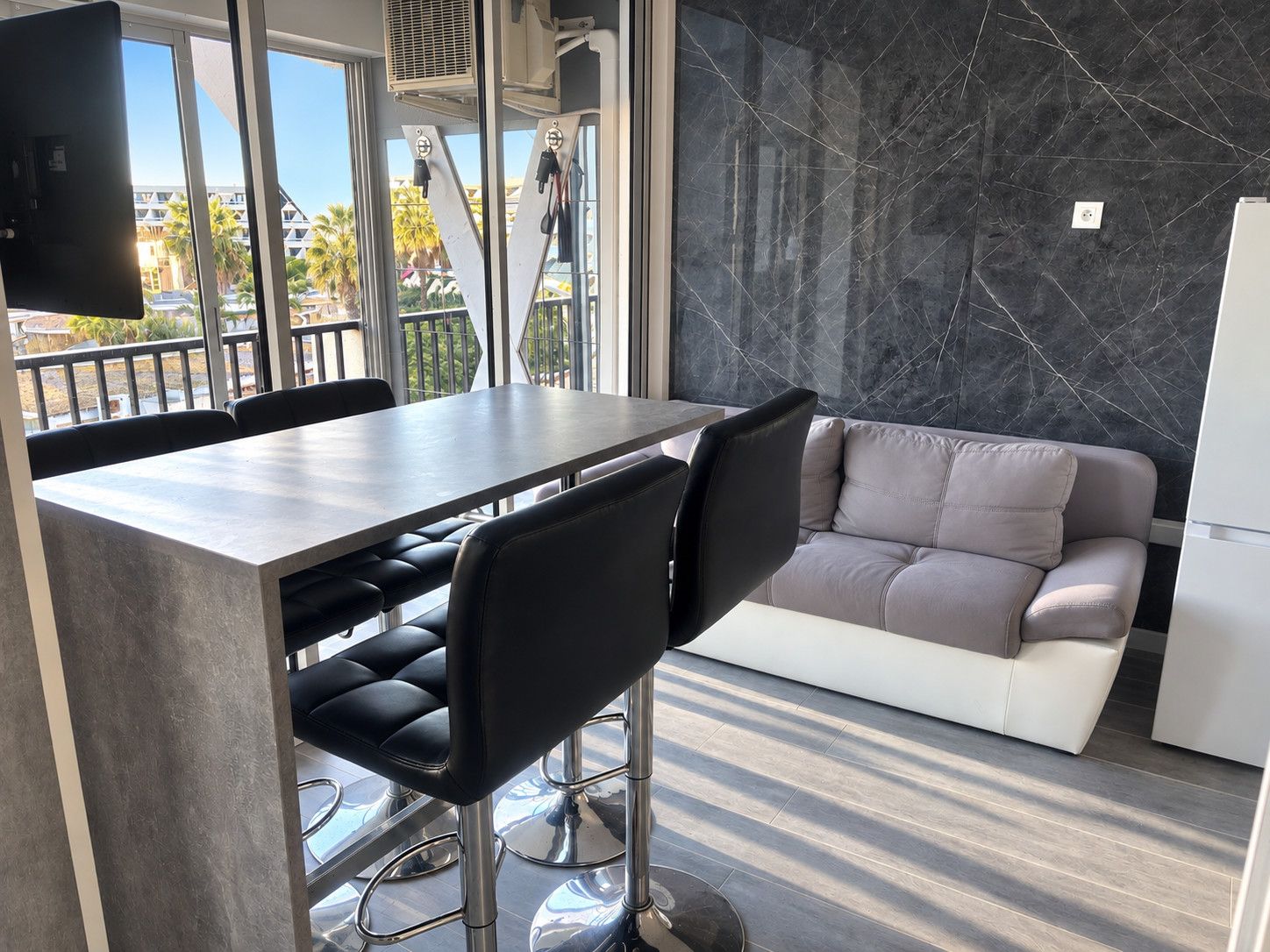 Una cocina moderna con salpicadero de mármol, una mesa de comedor con sillas y un sofá.