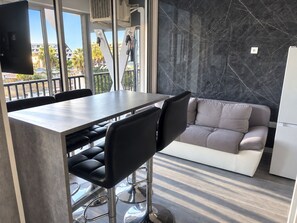 A modern kitchen with a marble backsplash, a dining table with chairs, and a sofa. - Naturiste Cap d'Agde Héliopolis F 90 (Agde)