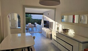 A modern kitchen with a dining area, a TV, and a view of the outdoors. - Naturiste Cap d'Agde Villa Héliovillage 20 (Agde)
