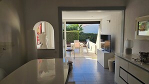 A modern kitchen with a large island, a dining area with a table and chairs, and a view of the outdoor patio. - Naturiste Cap d'Agde Villa Héliovillage 20 (Agde)