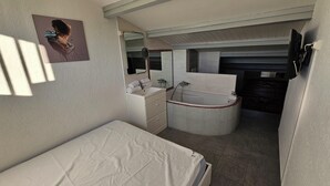 A small, compact room with a single bed, a bathroom with a bathtub, and a mirror. - Naturiste Cap d'Agde Villa Héliovillage 20 (Agde)