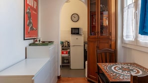 Une cuisine équipée d’un four à micro-ondes, d’un réfrigérateur, d’une armoire en bois et d’une horloge murale.