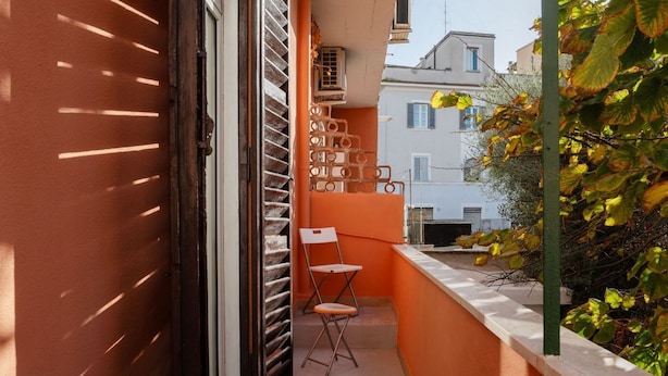 Un balcon étroit avec une chaise, une petite table et une fenêtre équipée de stores.