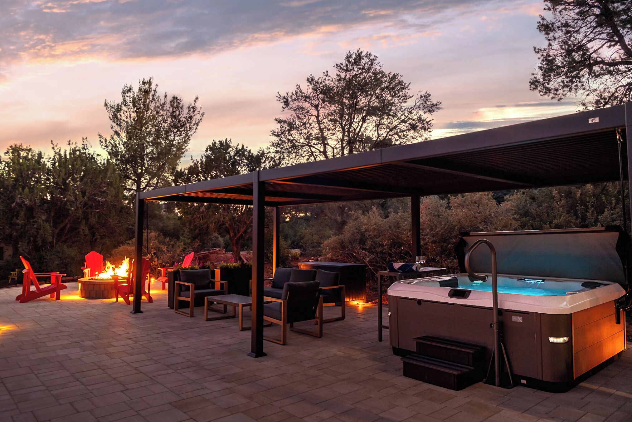 Eine Terrasse im Freien mit überdachter Sitzgelegenheit, Feuerstelle und Whirlpool.