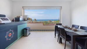 Un balcon équipé d’une table et de chaises pour prendre les repas, d’un four à micro-ondes et d’une poubelle.