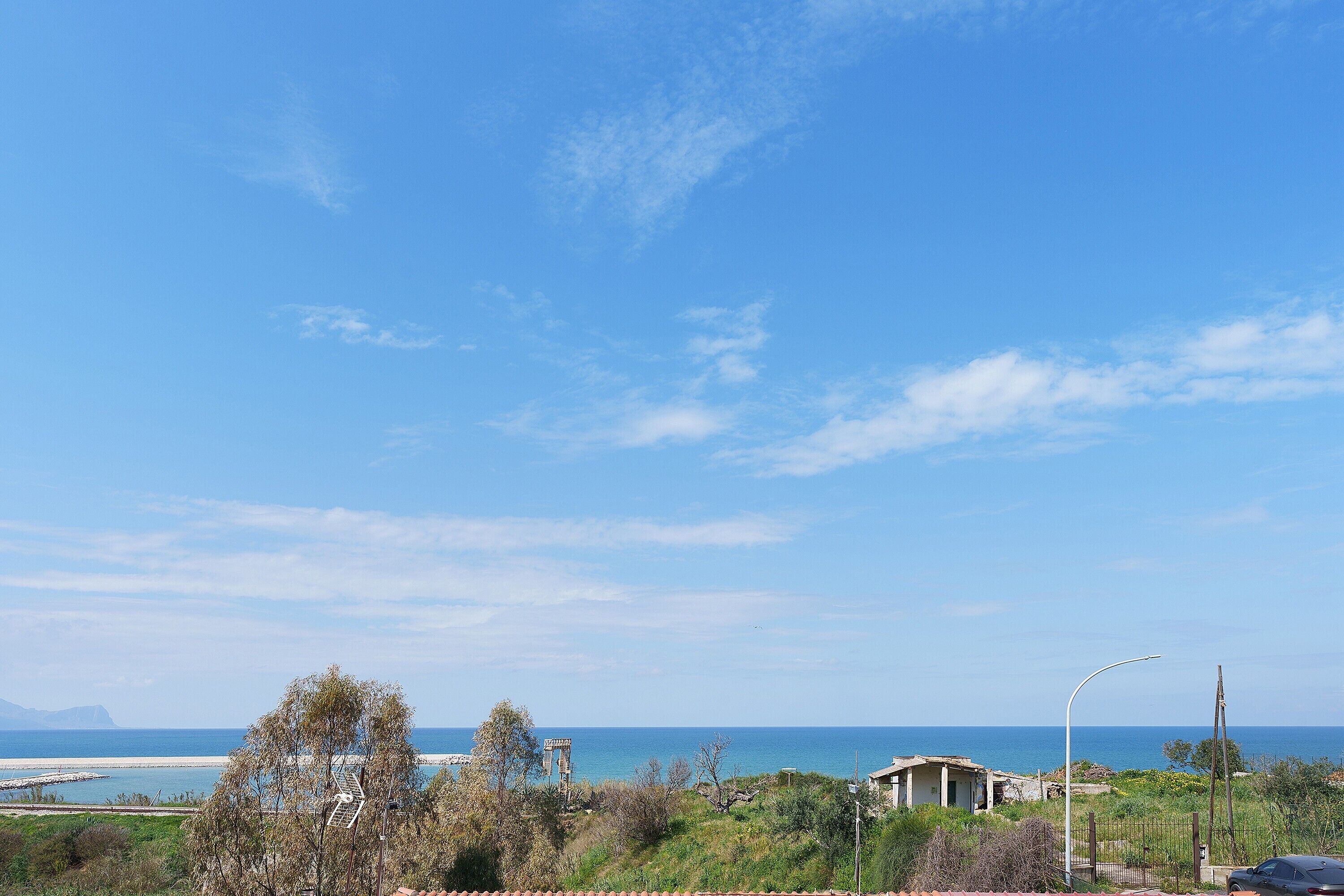 Vista costera con cielo despejado, una playa y un edificio de techo inclinado.