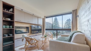 A modern kitchen with a large window, wicker chairs, and a sofa. - Lodge Belle Hutte - Proche des Pistes (La Bresse)