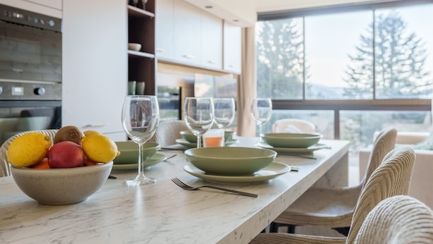 A modern kitchen with a marble countertop, a bowl of fruit, and wine glasses. - Lodge Belle Hutte - Proche des Pistes (La Bresse)