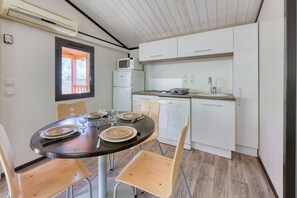 Una cocina compacta con armarios blancos, un microondas y un comedor con una mesa redonda preparada para dos.
