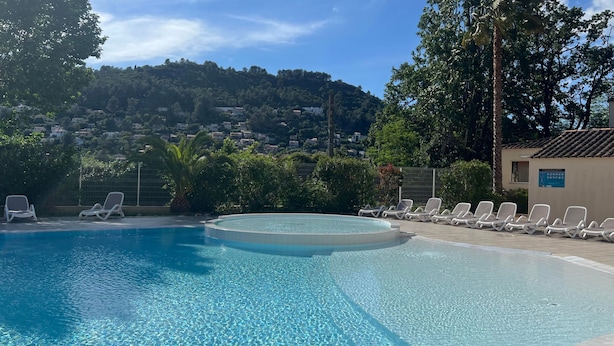 A swimming pool with lounge chairs, a view of a hillside with houses, and a building with a tiled roof. - Lou Pitchoun - Cottage pour 5 (Solliès-Toucas)