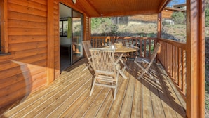 A wooden deck with a table and chairs, a glass door leading inside, and a view of the surrounding landscape. - Lou Pitchoun - Cottage pour 5 (Solliès-Toucas)