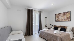 A hotel room with a bed, a sofa, a painting, and a window with curtains. - Room '4' with Sea View, Wi-Fi and Air Conditioning (Balestrate)