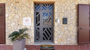 A stone facade with a decorative door, a potted plant, and a welcome mat. - Room '4' with Sea View, Wi-Fi and Air Conditioning (Balestrate)