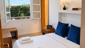A bedroom with a bed, bedside table, lamp, and a window with a view of greenery. - VillaBerria, 9Host, Pool, BBQ, Jcuzzi, Oasis Palma (Marratxí)