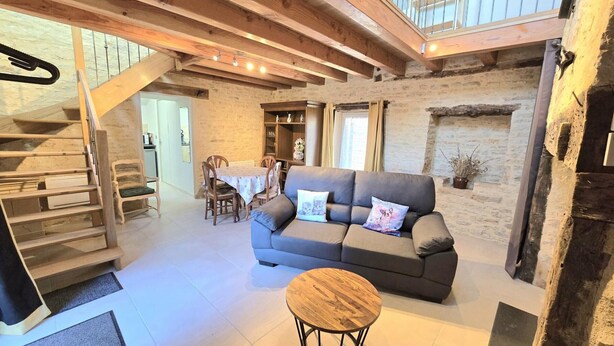 A cozy living room with a sofa, a round coffee table, and a staircase leading to an upper level. - Cozy house for couple with private spa in Périgord (Les Coteaux Périgourdins)