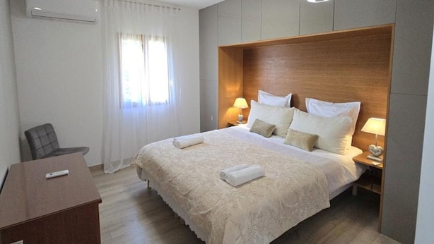 Ein Hotelzimmer mit einem großen Bett, zwei Nachttischlampen, einem Schreibtisch und einem Stuhl.