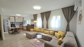 Ein modernes Wohnzimmer mit einer Eckcouch, einem Essbereich und einer Küche.