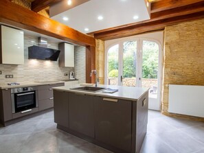 Una cocina moderna con una isla central, horno empotrado y un amplio ventanal con vistas a zonas verdes.