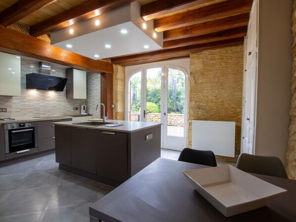 Una cocina moderna con una isla central, horno empotrado y un amplio ventanal.