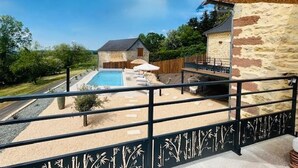 A pool area with a stone building, a wooden deck, and a fenced garden. - Large Family House with Private Pool and Pets Welcome (Coubjours)