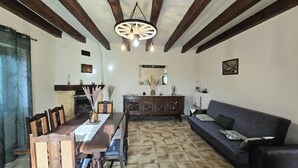 A dining area with a wooden table and chairs, a sofa, and a fireplace. - Comfortable Country House in Dordogne (Saint-Rabier)