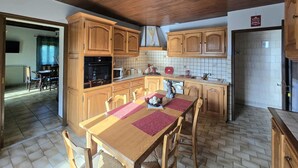 A kitchen with wooden cabinets, a dining table with chairs, and a tiled backsplash. - Comfortable Country House in Dordogne (Saint-Rabier)