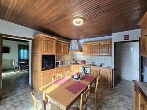 A kitchen with wooden cabinets, a dining table with chairs, and a tiled backsplash. - Comfortable Country House in Dordogne (Saint-Rabier)