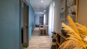 A hallway with a wooden floor, a staircase, and a wall with abstract art. - Cottage for 11 with parking, spa, pets allowed (Paulin)